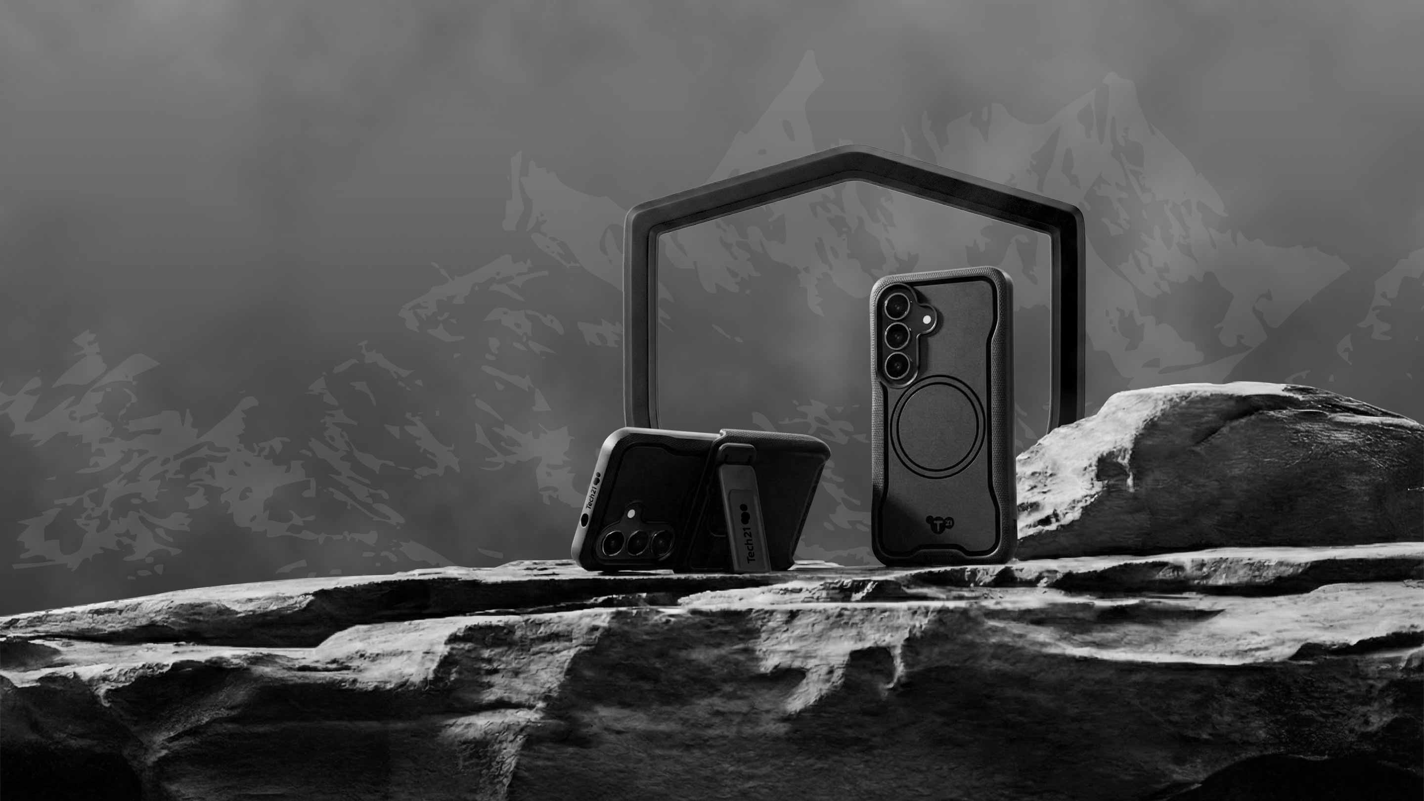 Two EvoGuard cases for Samsung S26 on a rock in front of a mountain range, one is in portrait mode standing tall, while the other lays in landscape mode held up by its view stand