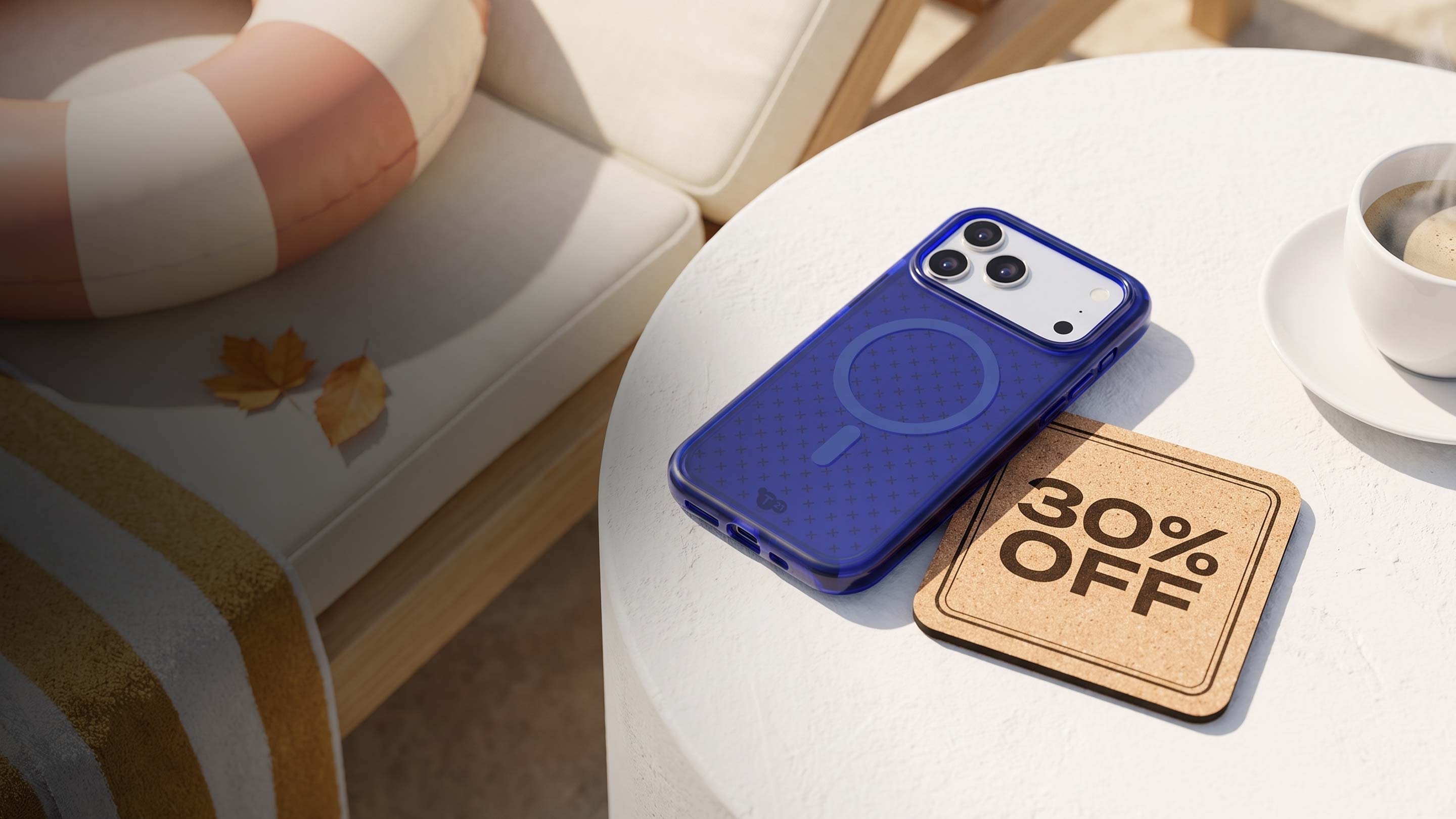 An iPhone in blue Tech21 case sits on a table next to a steaming up of coffee with a coaster next to it that reads: 30% OFF